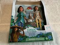 Front of Disney Raya The Last Dragon doll set packaging showing Raya, Namaari dolls, Tuk Tuk and baby Noi figures visible through clear box front.