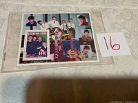 Photo of Burkina Faso Beatles Showbizz stamp with photographic background featuring band members and guitars in protective plastic case