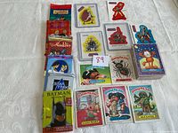Photo showing an assortment of vintage and mixed trading card packs and loose cards from various brands including Garbage Pail Kids, Pokémon, Aladdin, Star Trek, and Batman Returns.