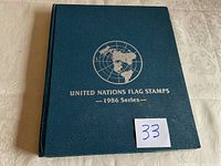Photo of green hardcover album titled 'United Nations Flag Stamps 1986 Series 1986 Series' with silver embossing.