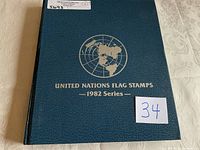 Photo of the front cover of the blue hardcover album titled 'United Nations Flag Stamps 1982 Series' with a white label and lot number sticker.