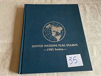 Blue hardcover spiral-bound album titled 'United Nations Flag Stamps - 1985 Series'