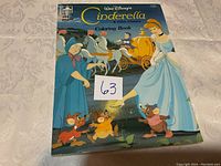 Front cover of the coloring book showing Cinderella with Fairy Godmother and other characters.