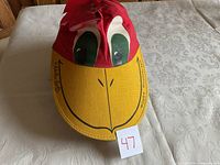 Red and yellow Woody Woodpecker character hat with face details and signature on brim