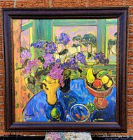 Full view of framed giclee print featuring purple flowers in a yellow vase on a blue table with a fruit bowl and window background
