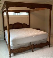 Full view of king size canopy bed with mattress, showing wooden frame, wicker woven diamond carved headboard, and mattress.
