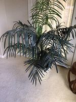 Artificial palm plant with lush green fronds in a ceramic-look planter.