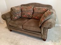 Front view of brown La-Z-Boy loveseat showing two reversible pillows with animal pattern design placed for decoration.