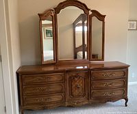 Front view of the entire dresser with mirror showing floral and diamond carving details on wood and brass drawer handles.