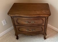 Front view of one Thomasville wood nightstand showing two drawers with matching pull handles and curved front design.