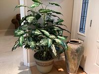 Full view of large artificial plant and ceramic pot beside it in a home setting, showing height and size relation.