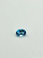 Top view of the oval-shaped blue topaz gemstone showing its color and facets.