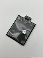 Clear round brilliant cubic zirconia gemstone in black plastic pouch with Lindenwolds branding.