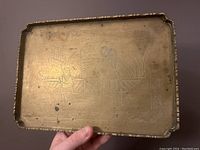 Full view of rectangular brass tray showing an engraved scene with two figures and architectural elements.