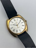 Front view of the watch face showing silver dial with Roman numerals, baton hands, and black leather strap