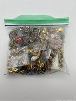 A transparent resealable plastic bag containing a large quantity of various lapel pins with Canadian symbols and colorful enamel details.