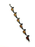 Full length view of the sterling silver bracelet with six teardrop amber stones showing the modernist design and lobster clasp.