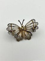 Close-up view of the butterfly pin showing detailed filigree wings and butterfly body design.