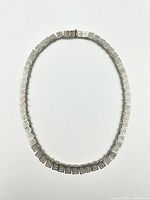 Full length view of silver Greek key necklace laid flat to show length and overall design.