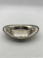Oval sterling silver nut dish displayed from the front showing floral bouquet embossed motifs and beaded edge.