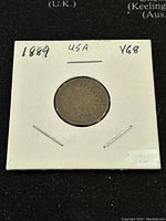 Obverse of 1889 US Indian Head penny in white holder showing Lady Liberty in Native American headdress, graded VG8.