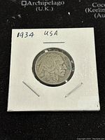 Front side of 1934 US Buffalo Nickel coin featuring Native American profile, mounted in white coin holder labeled '1934 USA'.