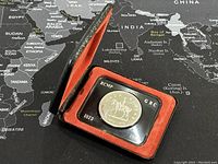 Coin inside original display case, showing red interior and black exterior case.