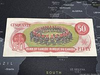 Back side of the 1975 Canadian fifty dollar banknote showing the Royal Canadian Mounted Police Musical Ride in a circular formation on horseback.