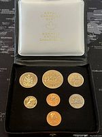 View of all 7 coins in original Royal Canadian Mint presentation box with white lid and dark blue base.