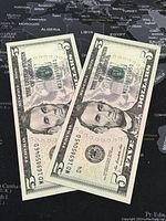 Two 2013 US $5 banknotes featuring Abraham Lincoln laid out showing front side with serial numbers.