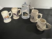 Overview of all five collectible steins arranged on black surface, showing different designs and styles.