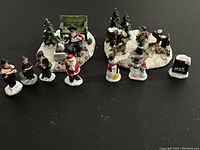 All nine Christmas village figurines arranged in groups on black background showing overall lot contents