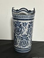 Side view of ceramic umbrella stand showing blue floral and ornamental patterns and scalloped top edge with handle.