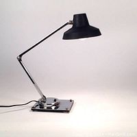 Side profile view of full articulating desk lamp showing arm, shade, base on white background