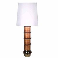 Front view of the complete lamp with white tapered lampshade, reed wrapped body with walnut fins visible, brass flared base.