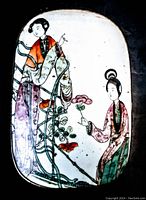 Top view of hand-painted porcelain plaque showing two figures and floral decoration.