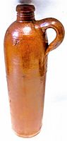 Full view of tall antique pottery gin bottle with salt glaze and handle.