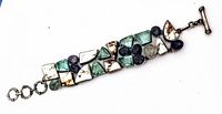 Full view of the vintage sterling silver bracelet showing the geometric shapes and round semi precious stone beads in green, black, and translucent colors with a toggle clasp.