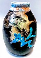 Front view showing hand-painted abstract design in blue, green, white, and tan on black matte surface.