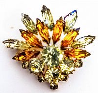 Close-up of vintage rhinestone brooch with amber, pale yellow, and clear rhinestones set in a fan shape.