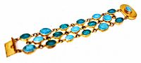 Photo of vintage gold plated bracelet showing three rows of oval blue glass stones and the push lock clasp.