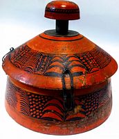 Side angle of vintage tribal spice box showing conical lid with knob, hand-painted red and black tribal patterns and metal clasps securing lid