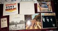 Seven albums and one book arranged together: Help!, White Album, Thirty Three & 1/3, A Twist of Lennon, All Things Must Pass, Abbey Road, Meet The Beatles!