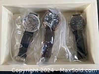 Three wristwatches displayed in a box, each individually wrapped in plastic bags.