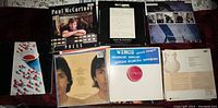Photo showing multiple Paul McCartney and Wings vinyl records and memorabilia spread out, including album covers, lyric sheets, and press booklets.