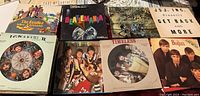 Photo showing seven Beatles vinyl records with varied cover art including Timeless II with a clock picture disc, Beatlemania, and Get Back and More.