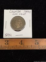 Photo of 1894 Canada one cent coin in protective holder with handwritten label and measurement scale.