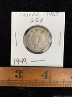 Obverse side of 1949 Canadian silver quarter showing King George VI profile and markings on white holder.