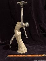 Front view of the Art Deco dancing lady candle holder showing the aluminum cast limbs and candle plate with textured resin body and base against black background.