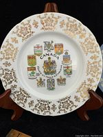 Canada commemorative plate with provincial coats of arms and gold decorative border on display stand